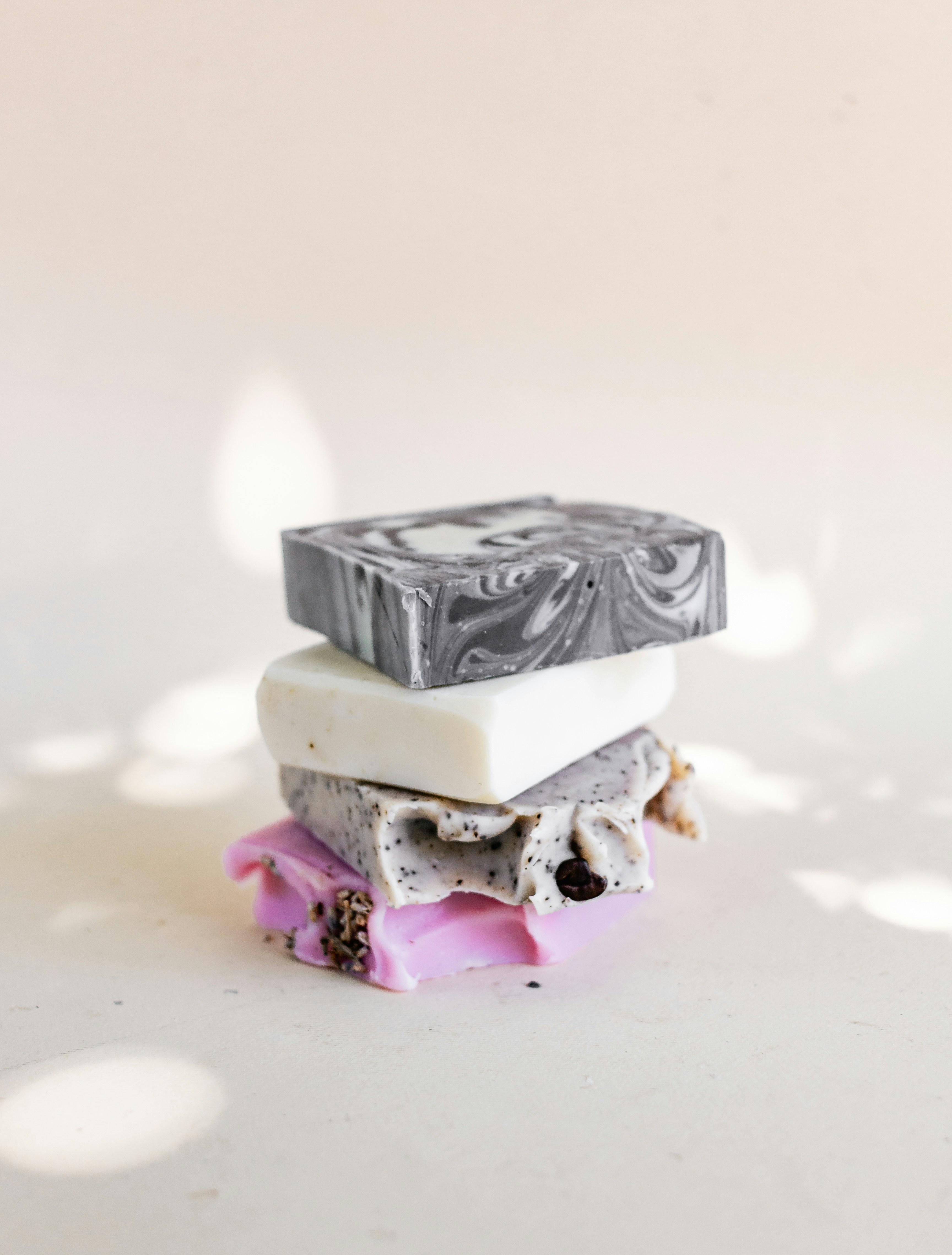 A colourful stack of marbled charcoal, creamy white and pink botanical soap bars